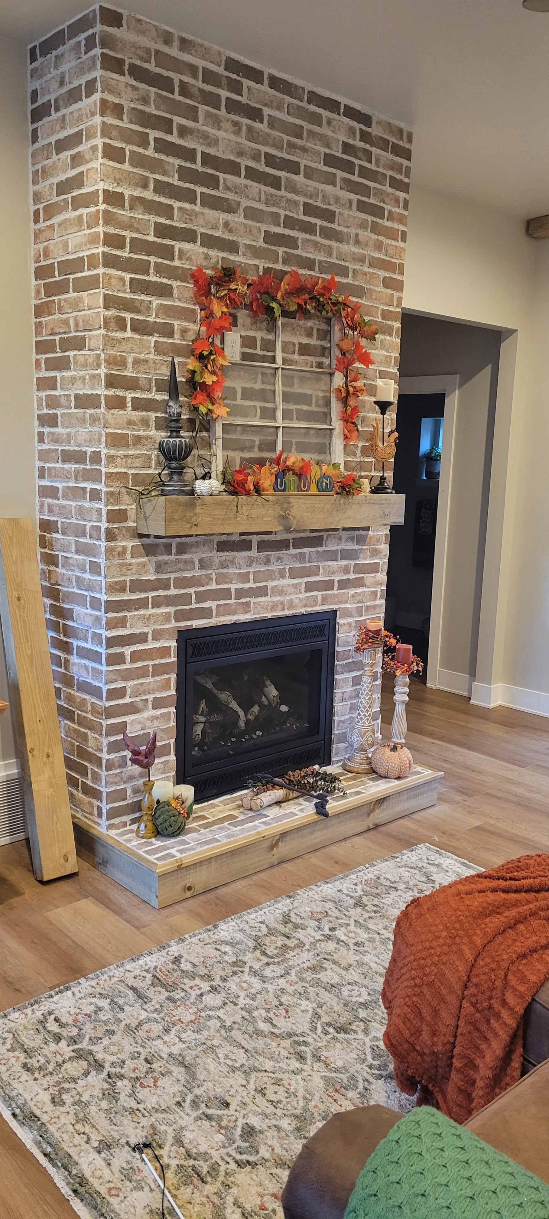 Brick fireplace with black insert, wood mantel, and tile hearth