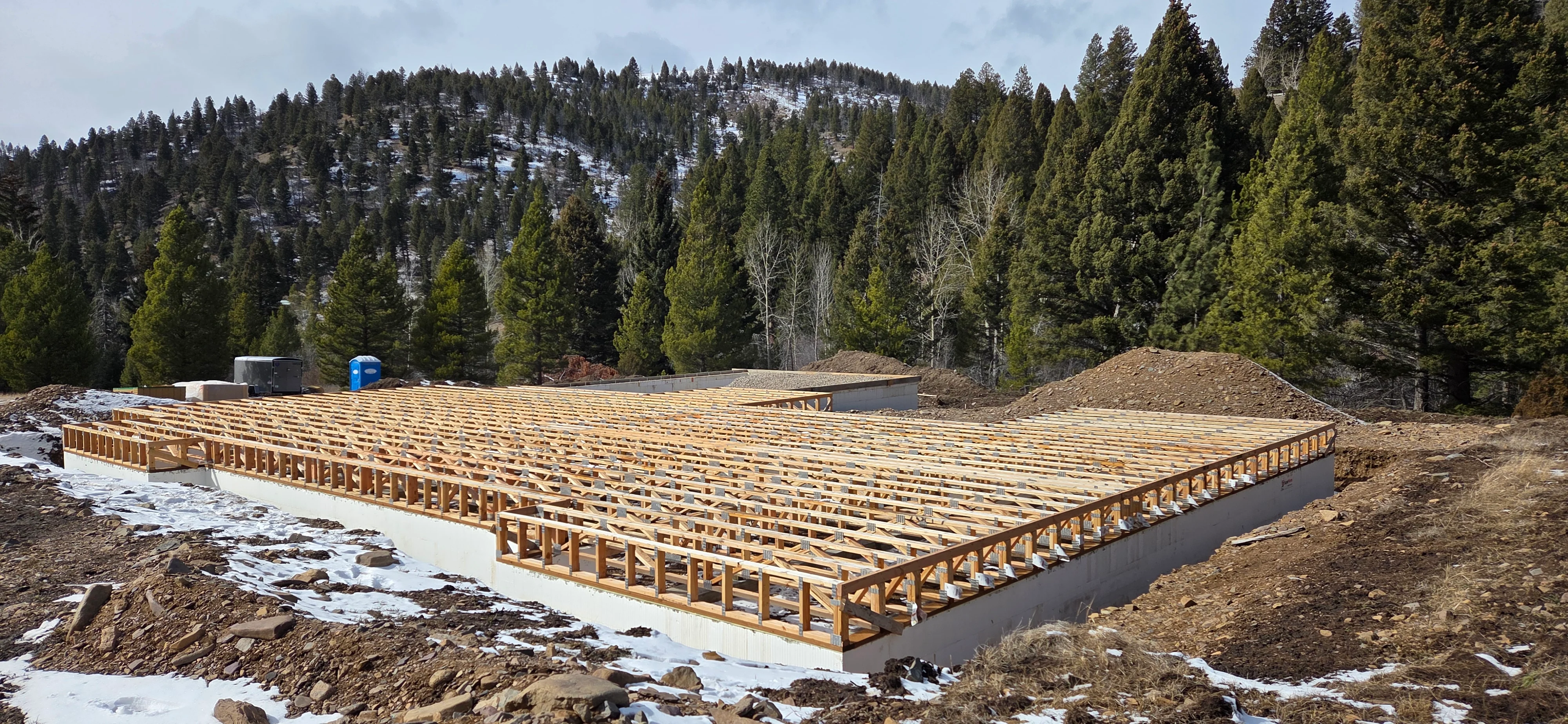 Concrete foundation with wood floor joists and framing in mountain forest setting