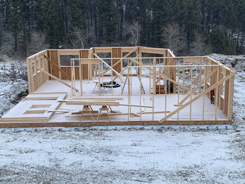 Wood-framed residential structure with concrete foundation, studs, trusses, and OSB sheathing during construction phase