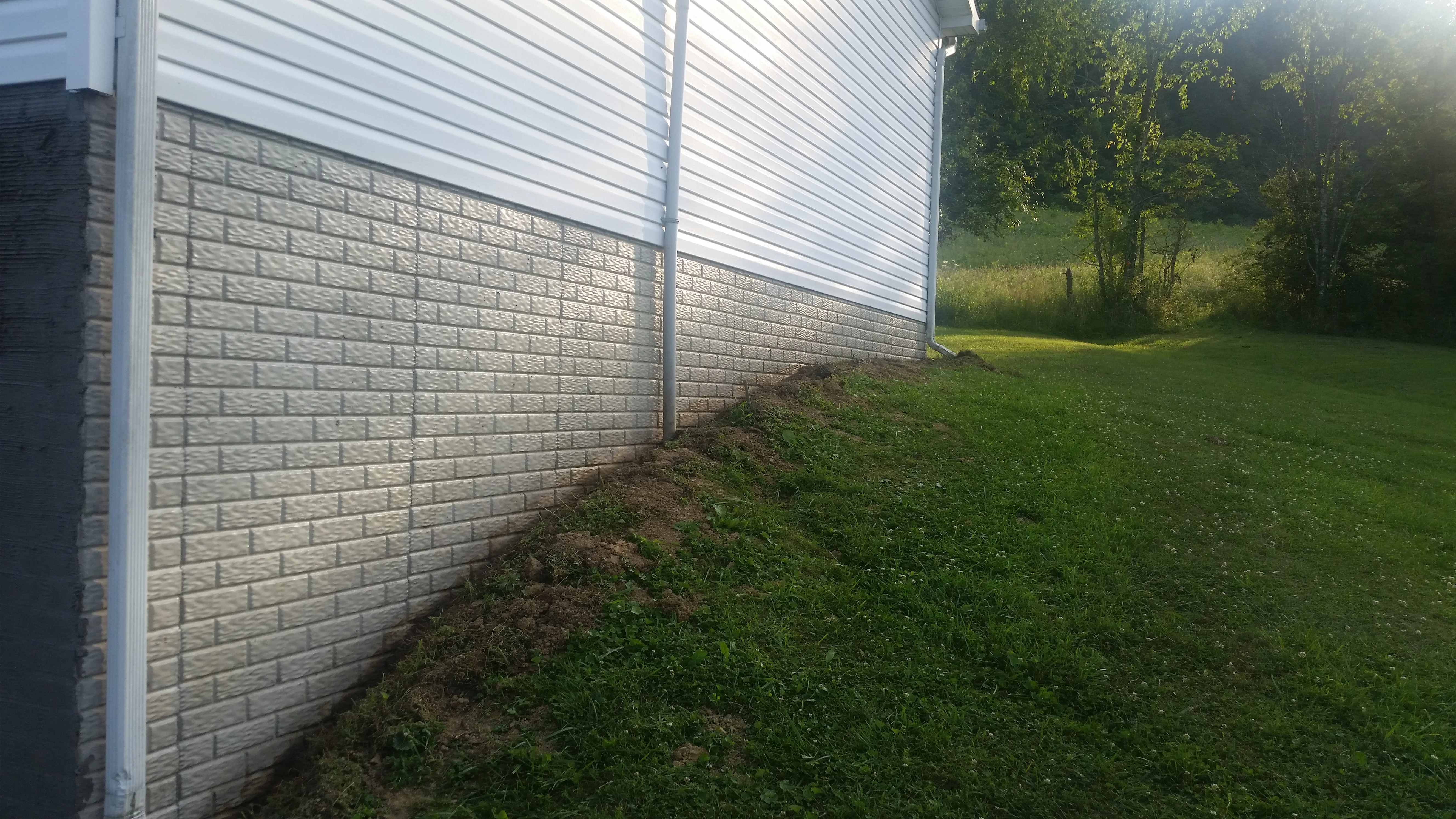 Concrete block foundation wall with white vinyl siding above, residential construction detail