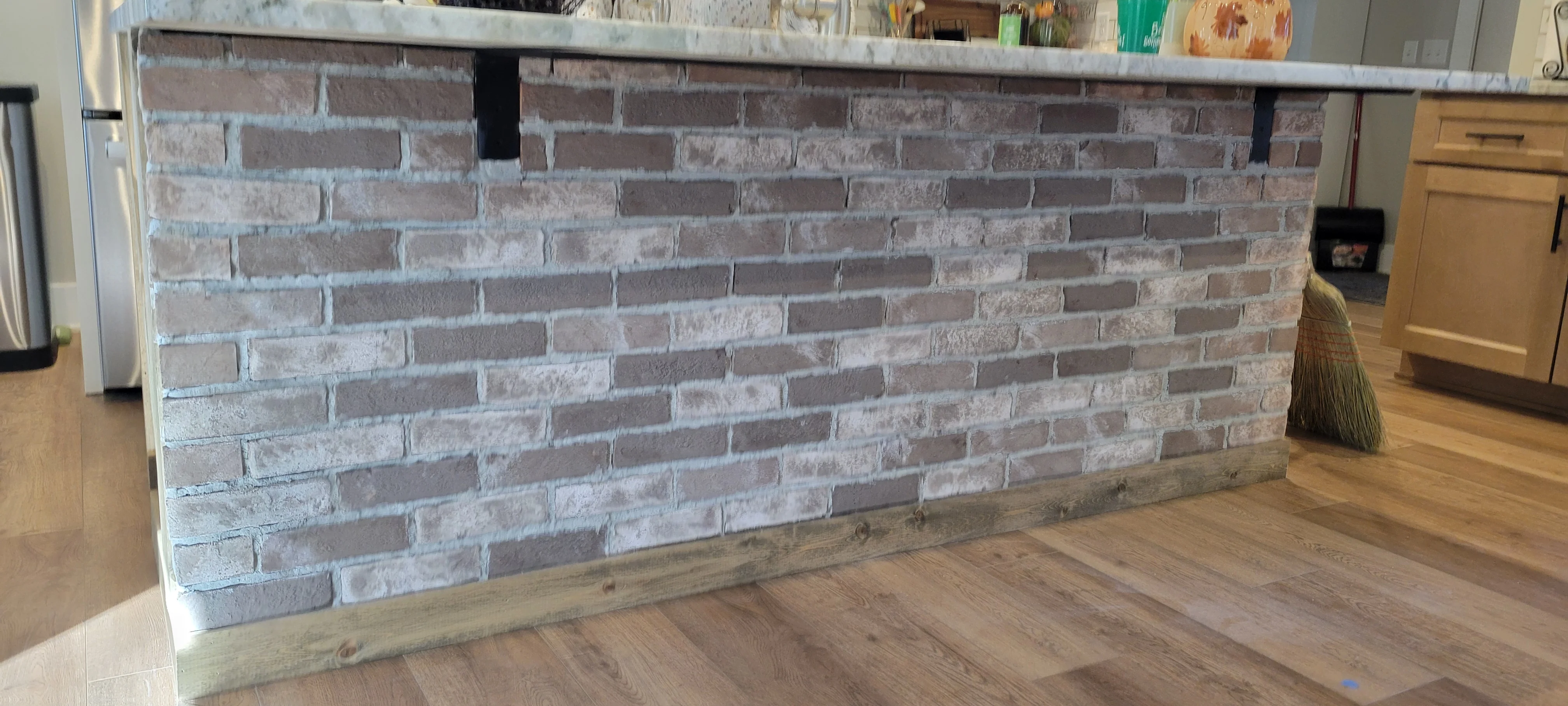 Gray stacked stone brick veneer fireplace with metal cap and mortar joints in kitchen