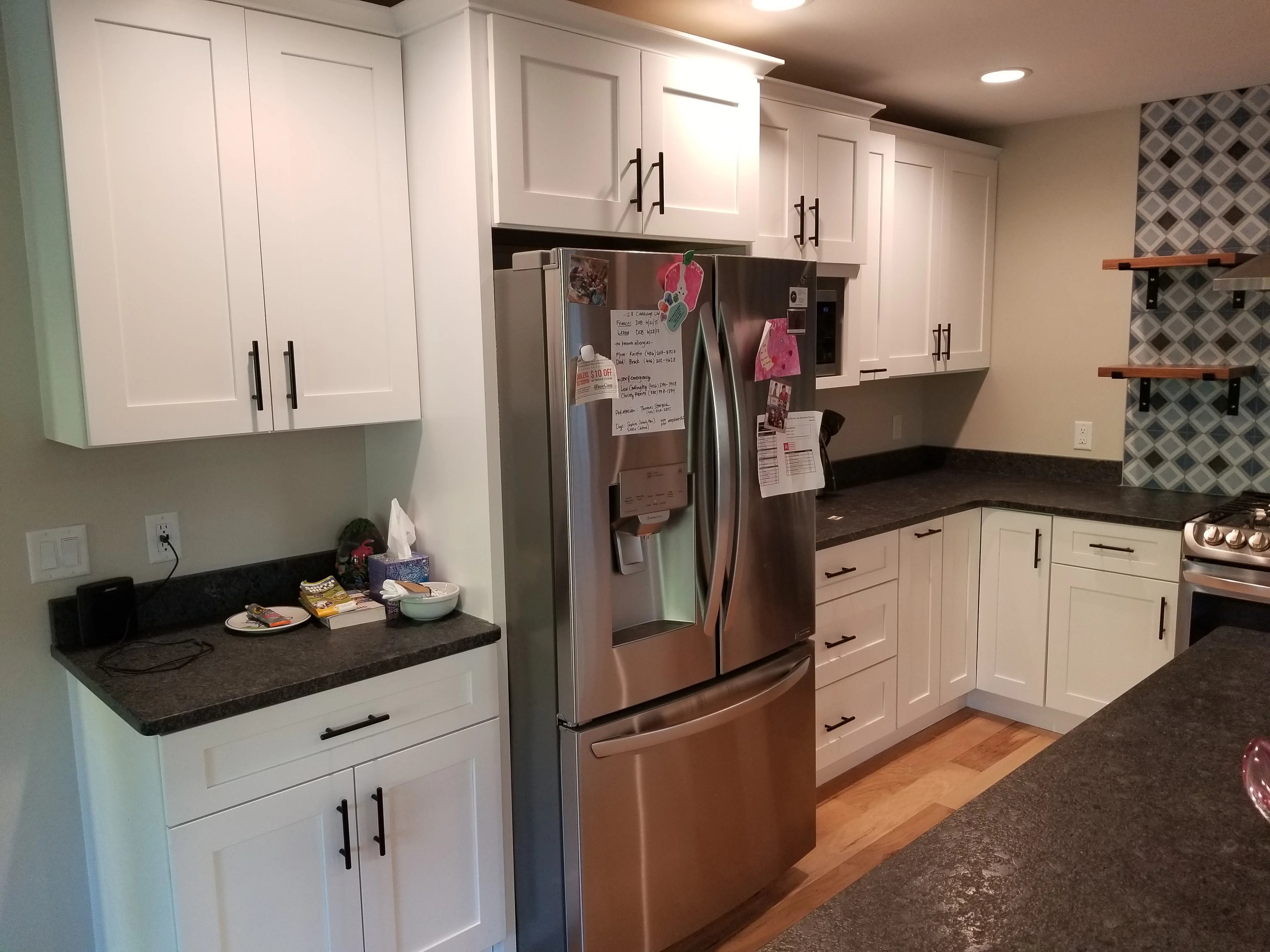 White kitchen cabinets, dark quartz counters, stainless steel appliances, geometric tile backsplash