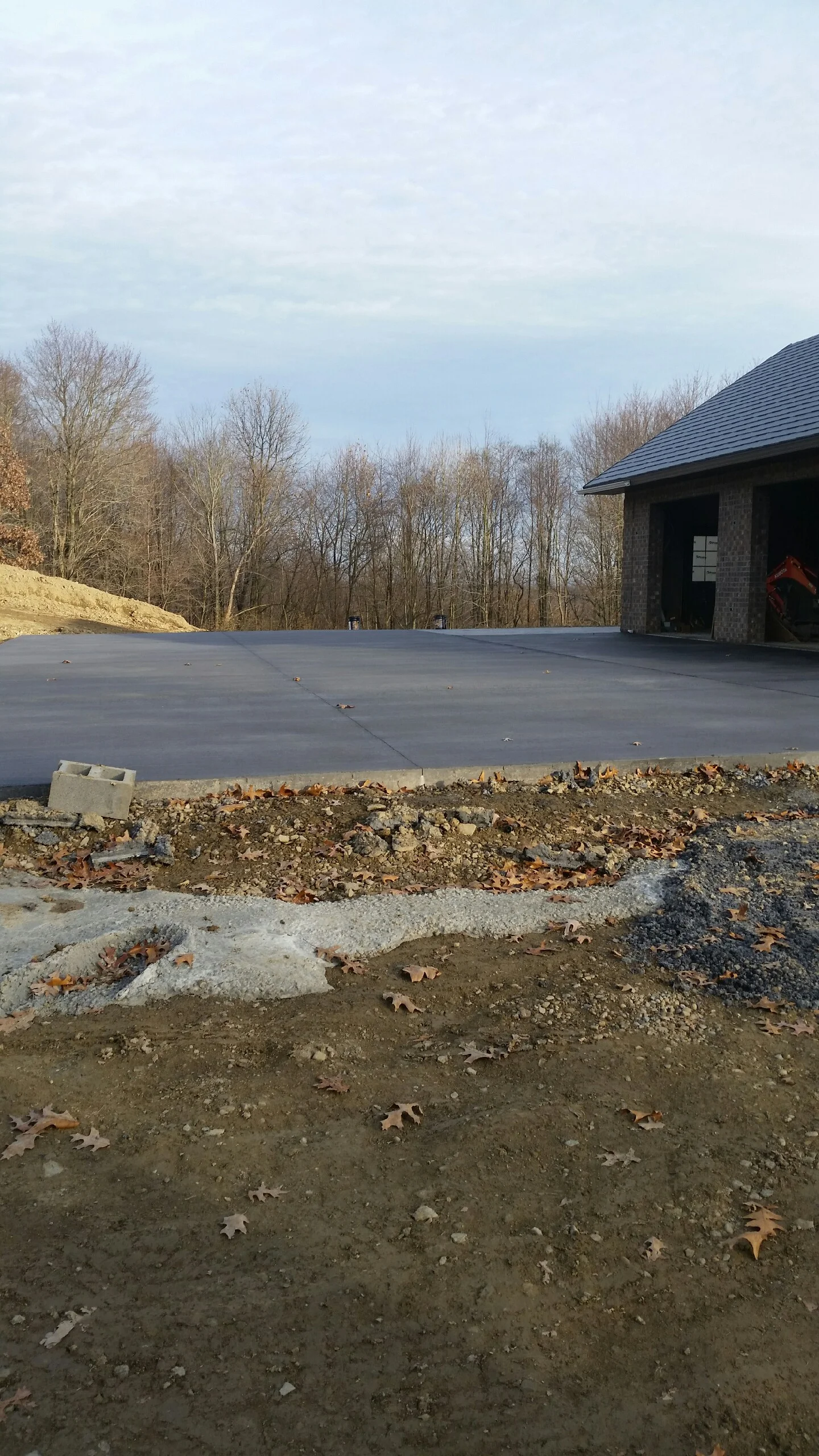 Finished asphalt driveway with concrete foundation and graded site preparation for residential construction