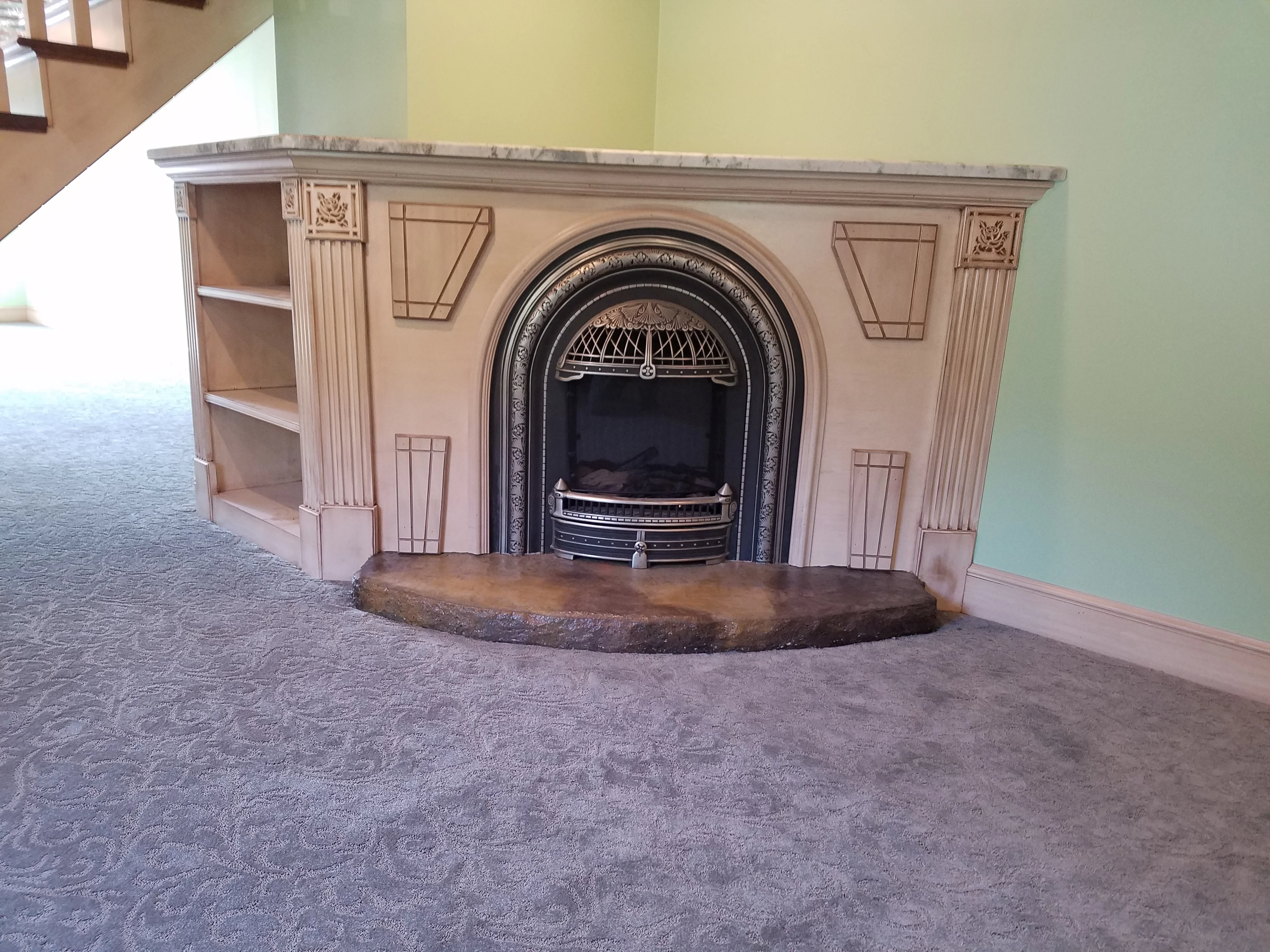 Cream wood fireplace mantel with fluted columns, black cast iron insert, and marble hearth