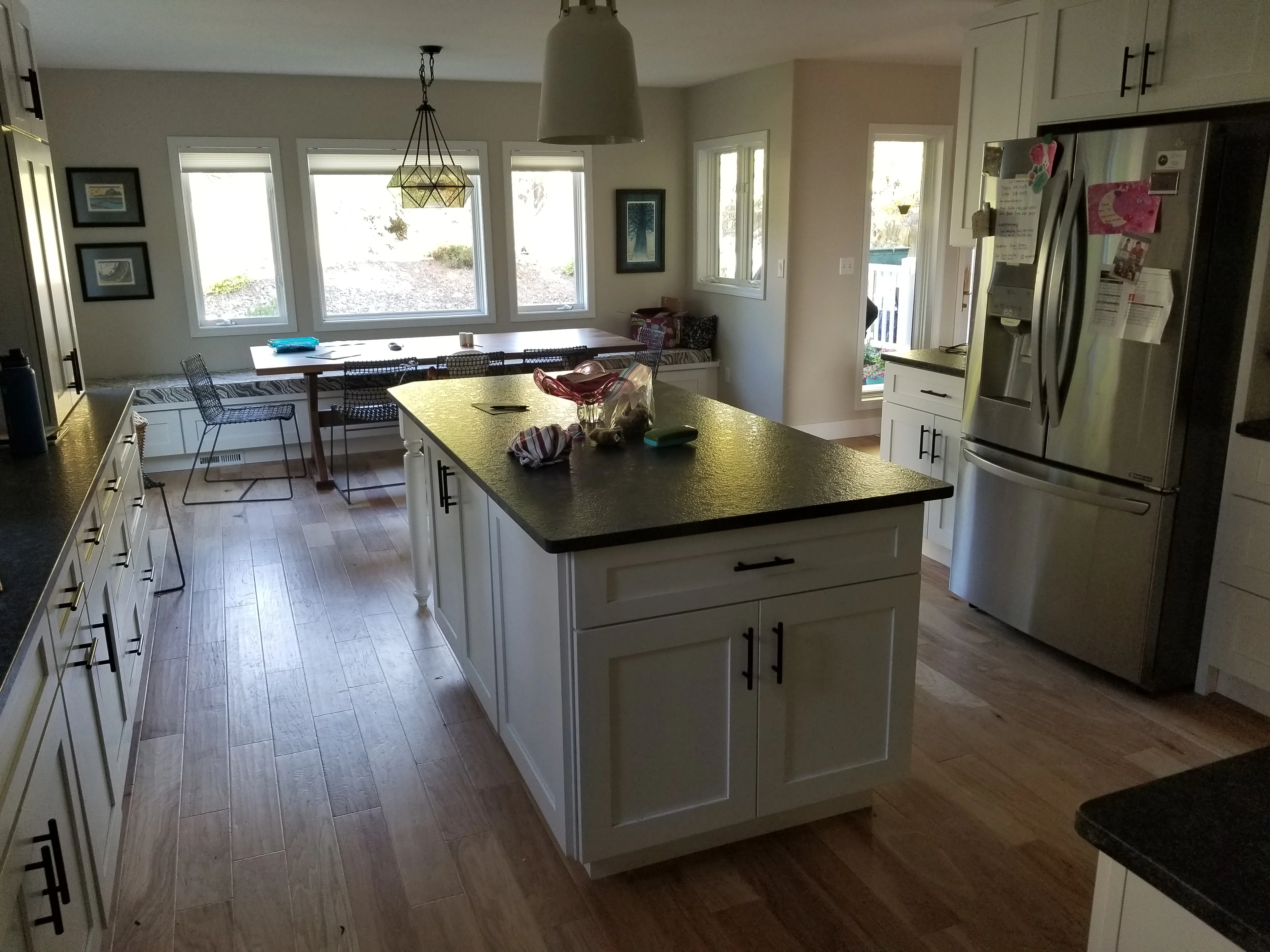 White kitchen cabinets, black quartz island countertop, stainless steel appliances, hardwood flooring