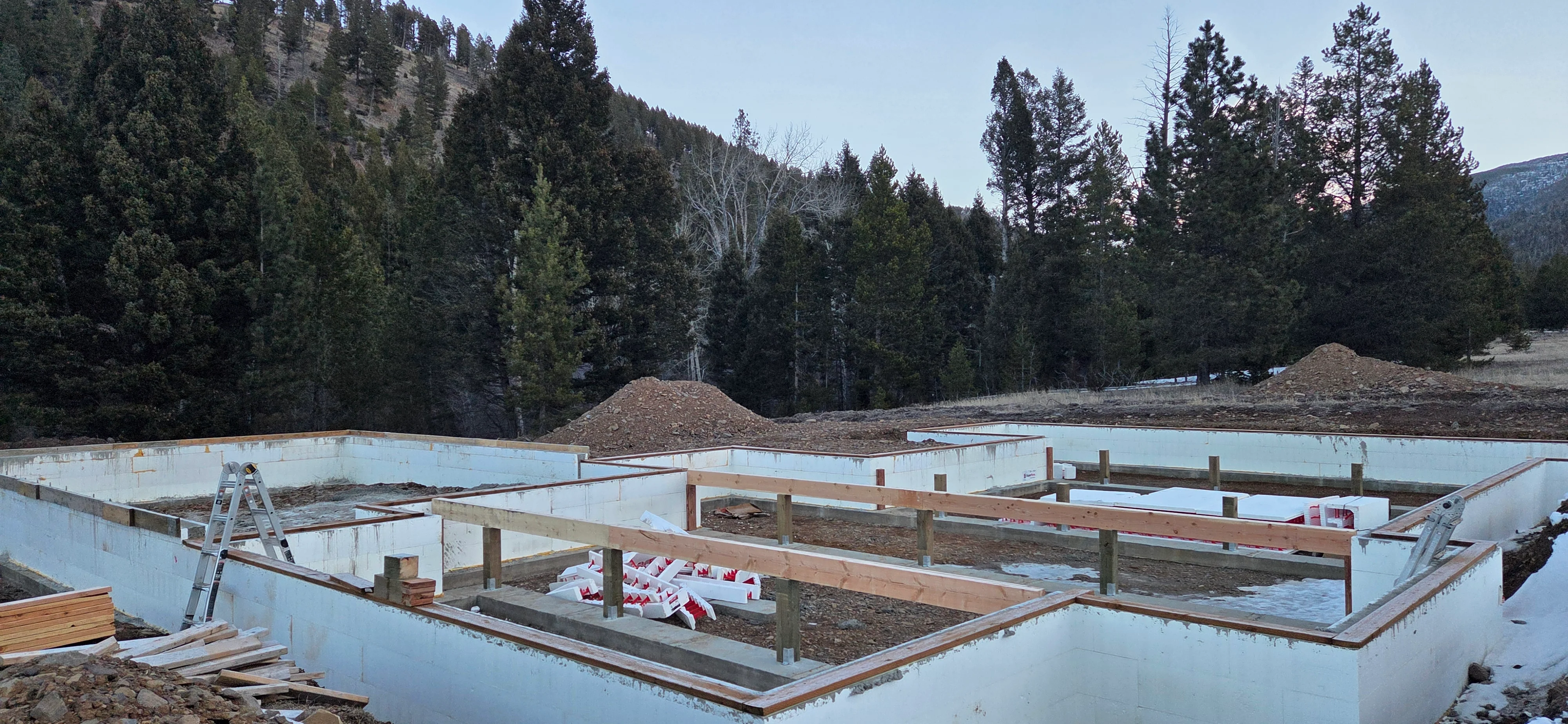 Concrete foundation with wood framing posts and structural elements on mountain construction site