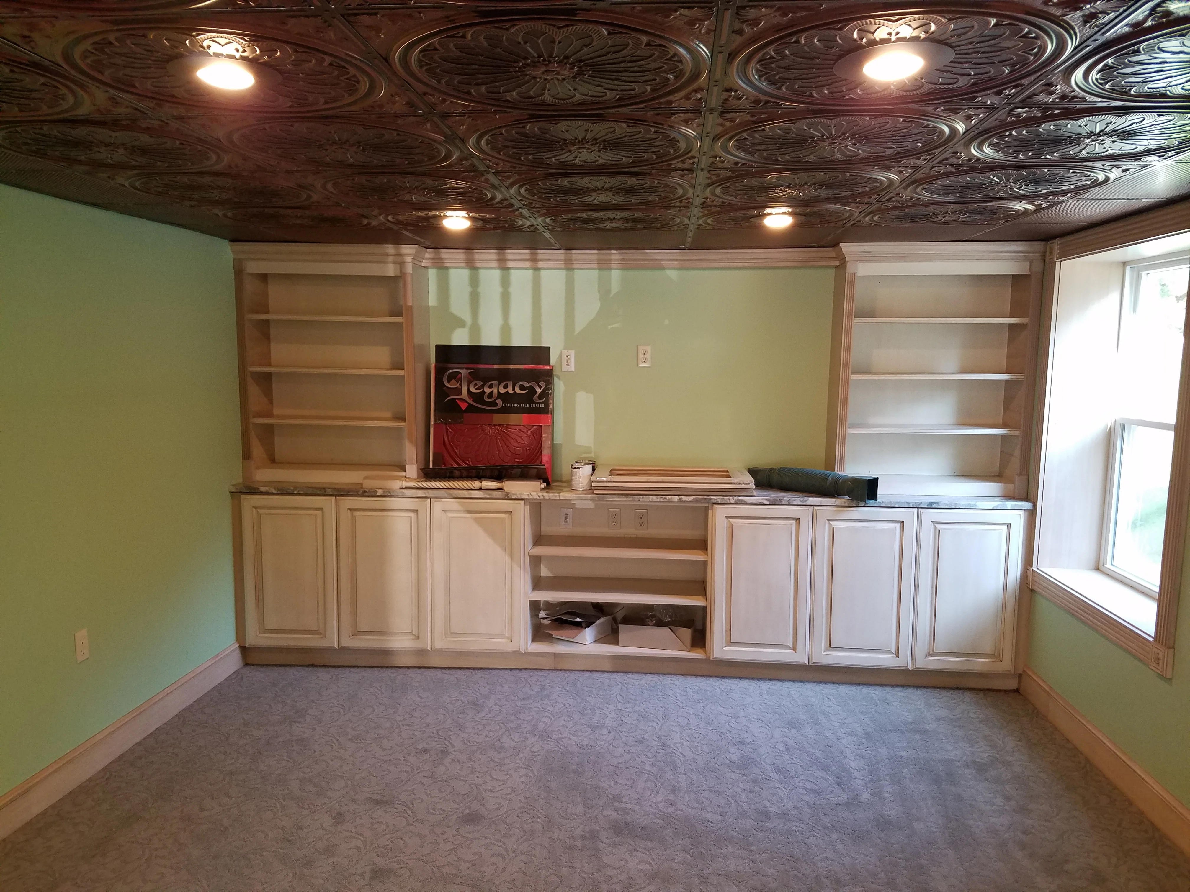 Custom wood cabinetry with shelving, tin ceiling tiles, and recessed lighting in finished basement