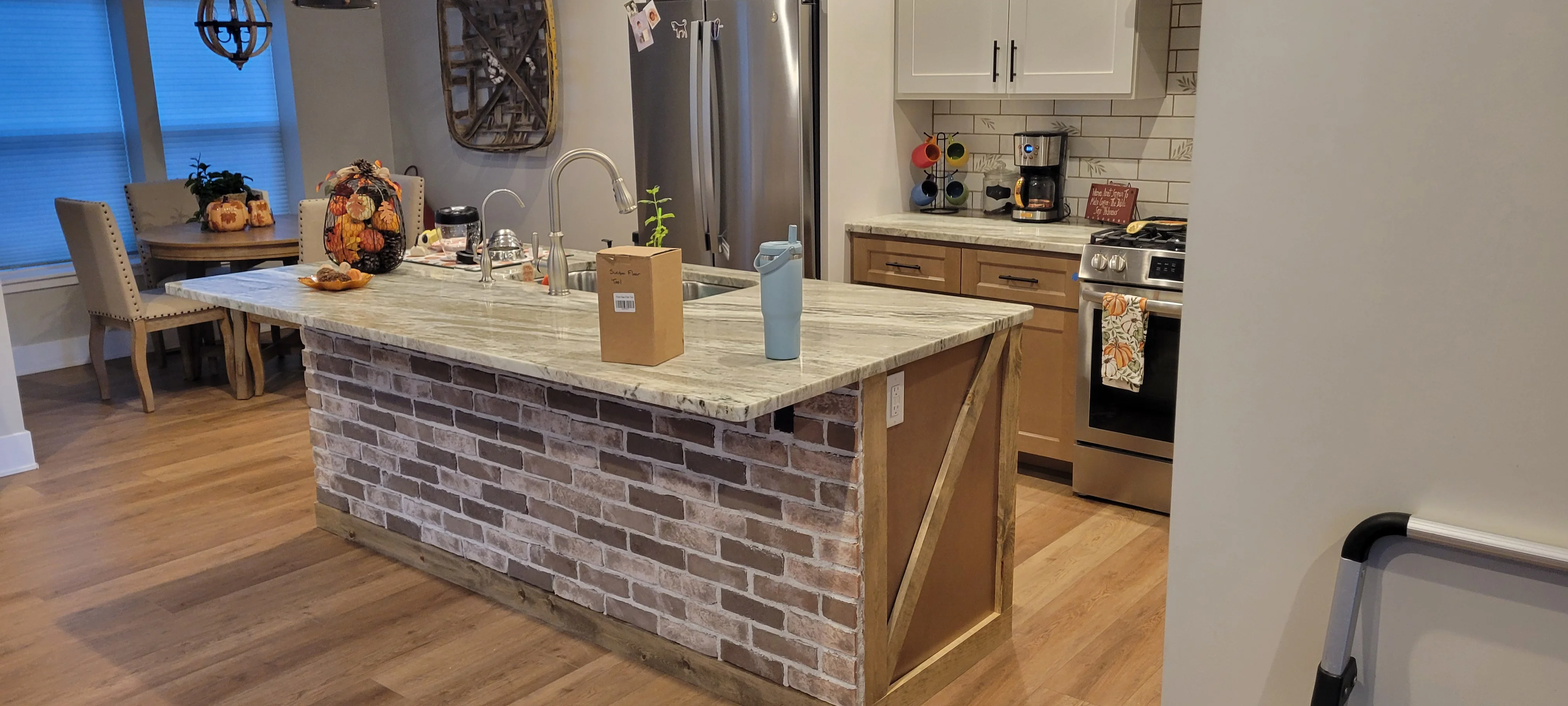 Kitchen island with gray brick base, marble countertop, and integrated sink with chrome faucet